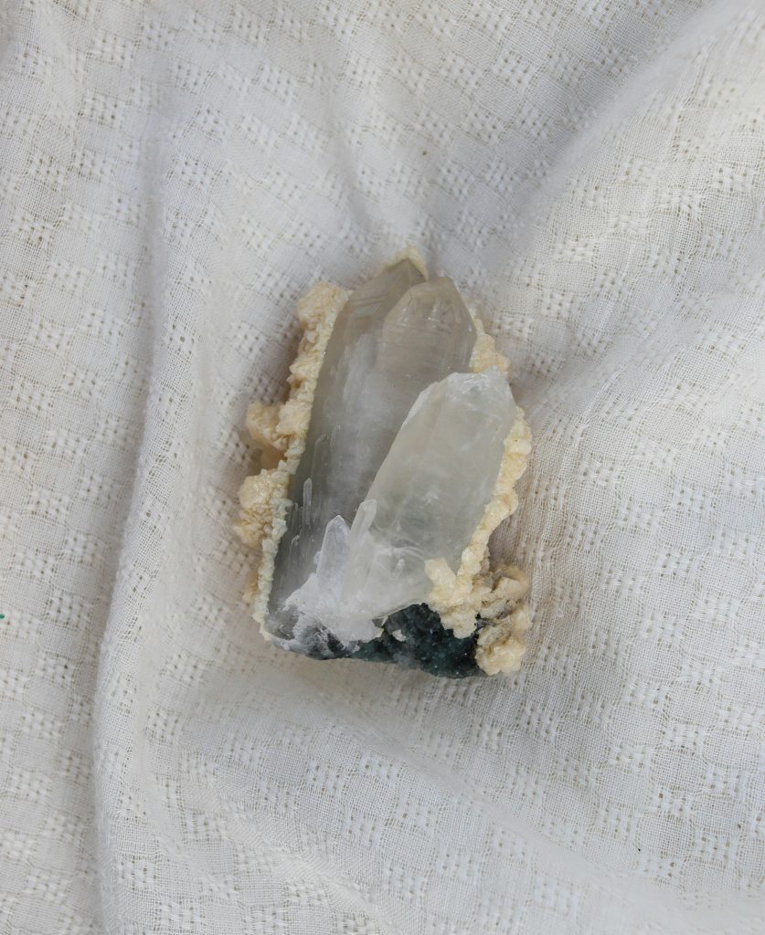 Close-up of a raw quartz crystal on a textured white fabric, highlighting natural beauty.
