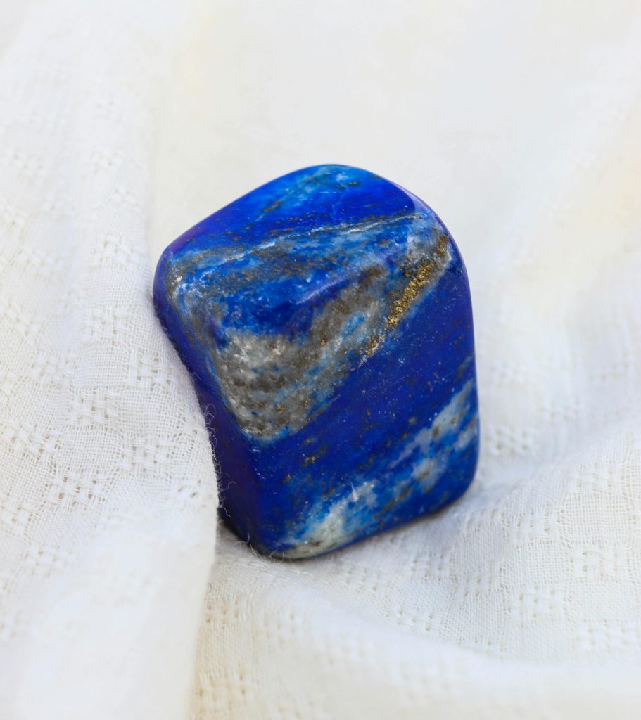Lapis Lazuli Detailed shot of a polished lapis lazuli stone resting on textured white fabric.