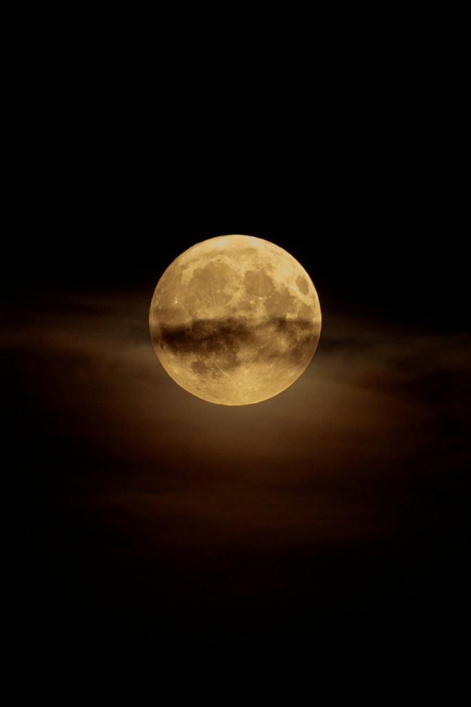 A captivating full moon shining brightly with a cloudy atmosphere at night, showcasing nature's beauty.