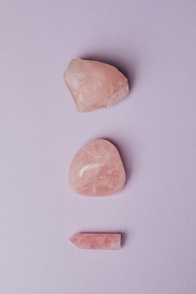 Rose Quartz A minimalist composition of three rose quartz stones on a soft purple background, showcasing their natural beauty.